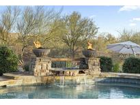 Close-up of pool with stone waterfall feature and fire bowls, perfect for evening swims at 27641 N 74Th St, Scottsdale, AZ 85266