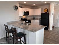 Modern kitchen features stainless steel appliances, granite countertops, and a breakfast bar with stool seating at 3175 W Santan Vista Dr, Eloy, AZ 85131