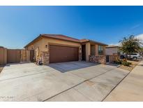 Beautiful home with a two-car garage, a stone accent wall, and desert landscaping in the front yard at 17577 W Desert Bloom St, Goodyear, AZ 85338