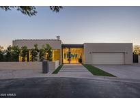 Contemporary home with sleek lines, neutral colors, mature trees, and a well-manicured front yard at dusk at 5910 N 45Th St, Phoenix, AZ 85018