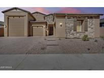 Charming single-story home featuring a stone facade, desert landscaping, and a three-car garage at 7694 W Desert Spoon Dr, Peoria, AZ 85383