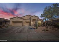 Charming, one-story stucco home featuring a three-car garage and desert landscaping at sunset at 9590 W Bajada Rd, Peoria, AZ 85383