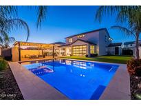 Inviting backyard with a sparkling pool, covered patio with string lights, and lush landscaping at 9937 E Harvest Rd, Florence, AZ 85132