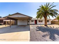 Charming single-story home featuring a covered carport, desert landscaping and a large palm tree in the front yard at 5209 W Hatcher Rd, Glendale, AZ 85302