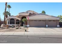 Inviting single-story home with a three-car garage, tiled roof and desert landscaping under clear blue skies at 12439 W Monte Vista Rd, Avondale, AZ 85392