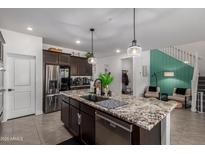 Modern kitchen featuring stainless steel appliances, granite countertops, and stylish pendant lighting at 16846 W Molly Ln, Surprise, AZ 85387