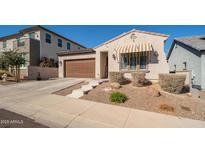 Charming home featuring a brown garage door, landscaped front yard, and a welcoming awning over the front window at 21150 W Minnezona Ave, Buckeye, AZ 85396