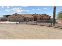 Charming single-story home featuring a three-car garage, desert landscaping, and neutral tones at 21433 W Caravaggio Ln, Wittmann, AZ 85361