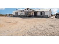 White single-story home featuring a covered porch and a large front yard at 21621 W Narramore Rd, Buckeye, AZ 85326