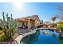 Inviting backyard showcasing a sparkling pool, covered patio, and lush desert landscaping at 1013 S Hazel Ct, Gilbert, AZ 85296