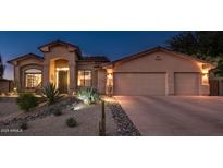 Charming single-story home with a two-car garage and desert landscaping illuminated at twilight at 17366 E Via Del Oro St, Fountain Hills, AZ 85268