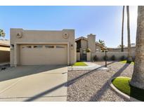 Beige single-story home with two-car garage, palm trees, a concrete driveway, and manicured desert landscaping at 25821 S Hollygreen Dr, Sun Lakes, AZ 85248