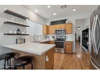 Bright kitchen with modern appliances, white countertops, wood cabinets, subway tile, and floating shelving at 40265 N Acadia Ct, Anthem, AZ 85086