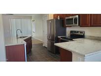 A well lit kitchen with modern appliances, dark wood cabinets and light granite countertops at 9121 W Alvarado St, Phoenix, AZ 85037