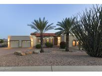 Charming desert home featuring a three-car garage, red tile roof, and desert landscaping with palm trees and decorative rocks at 15101 E Aspen Dr, Fountain Hills, AZ 85268