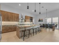 Bright kitchen featuring a large island with counter seating, natural wood cabinetry, and modern lighting at 38024 N 15Th Ave, Phoenix, AZ 85086