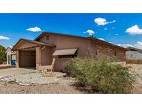 Tan single-story home with a front carport, low maintenance desert landscaping, and a blue sky backdrop at 485 S Pino Cir, Apache Junction, AZ 85120