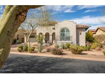 Inviting single-story stucco home showcasing manicured landscaping, tiled roof and a charming arched entry at 9266 E Desert Village Dr, Scottsdale, AZ 85255