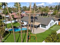 Aerial view of the property featuring a sparkling pool, play area, lush landscaping, and a covered patio at 10052 N 77Th St, Scottsdale, AZ 85258