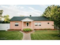 Charming single story home with a green lawn, manicured shrubbery and a light pink exterior at 102 W Washington Ave, Gilbert, AZ 85233