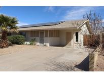 Charming single-story home featuring desert landscaping, a covered porch, and solar panels on the roof at 10621 N 115Th Ave, Youngtown, AZ 85363