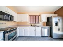 Well-lit kitchen with stainless steel appliances, white cabinetry, and a neutral countertop at 10851 E Clovis Ave, Mesa, AZ 85208