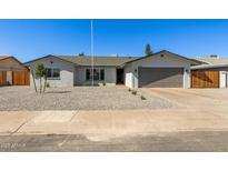 Charming single-story home with a gravel yard, wide driveway, and a gray two-car garage at 15028 N 35Th Ave, Phoenix, AZ 85053