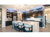 Gourmet kitchen featuring a large island with seating, stainless steel appliances, and modern lighting at 40195 N Hailey Ln, Queen Creek, AZ 85140