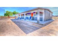 A single-story home featuring a red front door, blue trim, and a cozy front porch with two chairs at 9066 N Thunderbird Rd, Maricopa, AZ 85139