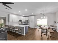 Modern kitchen features white cabinets, quartz counters, stainless appliances, and a spacious dining area at 1366 W Santa Gertrudis Trl, San Tan Valley, AZ 85143