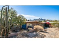 Charming single-story home features a blue front door, desert landscaping, and mountain views at 13023 N Joan D Arc Ave, Phoenix, AZ 85032