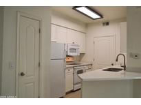 A bright kitchen has white cabinets, a white countertop and appliances at 1701 E Colter St # 191, Phoenix, AZ 85016