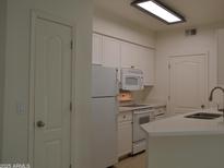 Bright kitchen features white appliances, white cabinetry, and quartz countertops at 1701 E Colter St # 191, Phoenix, AZ 85016