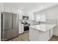 Modern kitchen with stainless steel appliances, white cabinets and countertops, and decorative backsplash at 6173 N Granite Reef Rd, Scottsdale, AZ 85250