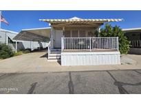 Charming home showcasing a covered front porch with awning and white railings, complemented by a blue sky backdrop at 8700 E University Dr # 1024, Mesa, AZ 85207