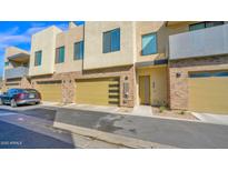 Modern townhome showcasing a brick facade and gold garage doors on a sunny day at 901 S Smith Rd # 1013, Tempe, AZ 85281