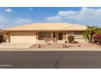 Charming single-story home showcasing a well-manicured front yard with lush landscaping and a two-car garage at 10856 E Kiva Ave, Mesa, AZ 85209