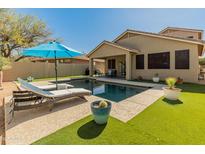 Backyard pool with lounge chairs and blue umbrella at 39526 N White Tail Ln, Anthem, AZ 85086