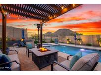 Relaxing backyard with a sparkling pool, hot tub, fire pit, and comfortable seating area under pergola at 12924 W Caraveo Pl, Peoria, AZ 85383