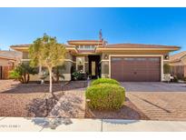 Charming home with manicured landscaping, a paver driveway, and an American flag on a clear, blue-sky day at 18635 W Miami St, Goodyear, AZ 85338