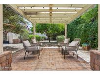 Inviting outdoor seating area with brick pavers, pergola, mature trees, and comfortable chairs at 385 E Coronado Rd # 5, Phoenix, AZ 85004