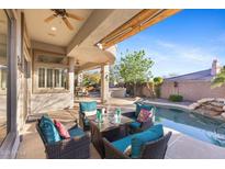 Covered patio area featuring wicker furniture and views of the pool and desert landscaping at 42047 N Moss Springs Rd, Anthem, AZ 85086