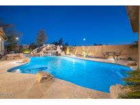 Backyard pool area with stone features, slide, waterfall, and lush landscaping at 7157 E Ivyglen Cir, Mesa, AZ 85207