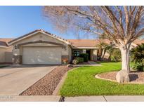 Charming home features a well-manicured lawn, desert landscaping, and a two-car garage at 950 W Cooley Dr, Gilbert, AZ 85233