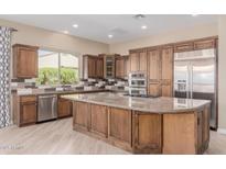 Spacious kitchen features stainless steel appliances, granite counters, custom backsplash, and a center island with a gas cooktop at 1474 E Elysian Pass, Queen Creek, AZ 85140