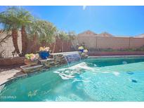 Inviting backyard pool with a beautiful waterfall feature and desert landscaping at 16763 W Adams St, Goodyear, AZ 85338
