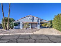 Charming blue home with a well-manicured desert landscape and covered carport at 654 S 83Rd Way, Mesa, AZ 85208