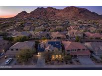 Stunning aerial view of a home with solar panels, mountain views, and desert landscaping at sunset at 8362 W Rosewood Ln, Peoria, AZ 85383