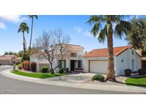 Inviting desert home with a red tile roof, green lawn, palm trees, and a circular driveway at 10076 E Calle De Cielo E Cir, Scottsdale, AZ 85258