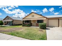 Charming single-story home with a well-manicured lawn, beautiful landscaping, and a driveway leading to an attached garage at 10216 N 95Th Dr # A, Peoria, AZ 85345